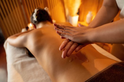 Masseur hands pouring aroma oil on woman back. Masseuse prepare oil massage procedure for customer at spa salon in luxury resort. Aroma oil body massage therapy concept. Quiescent