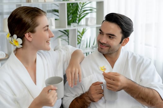 Beauty or body treatment spa salon vacation lifestyle concept with couple wearing bathrobe relaxing with drinks in luxurious hotel spa or resort room. Vacation and leisure relaxation. Quiescent