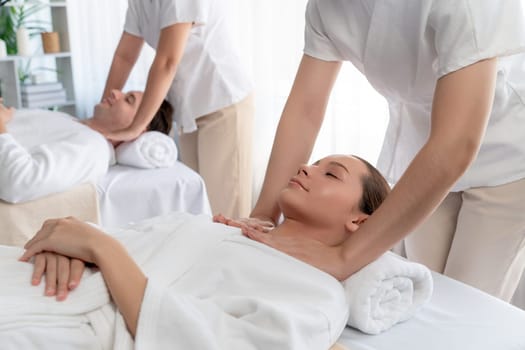 Caucasian couple customer enjoying relaxing anti-stress spa massage and pampering with beauty skin recreation leisure in day light ambient salon spa at luxury resort or hotel. Quiescent