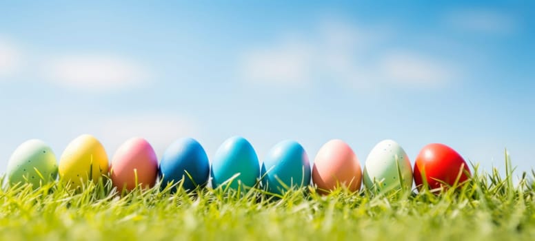 A vibrant display of colorful Easter eggs lined up in a row on lush green grass under a clear blue sky, celebrating the joy of Easter.