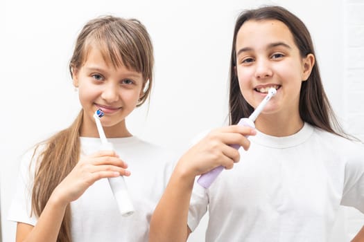 Portrait of two beautiful girls kids with perfect smile holding toothbrushes. Child dental care, oral hygiene concept. High quality photo