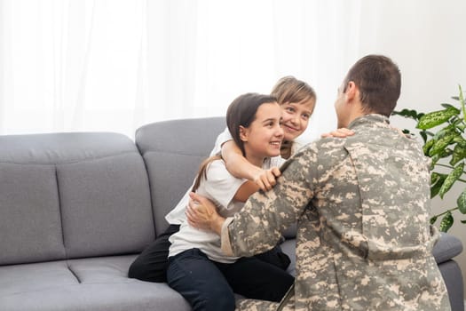 happy positive smiling soldier man in camouflage sitting with his daughter on sofa, looking how his kid grown when he was in army, returning home from war. High quality photo