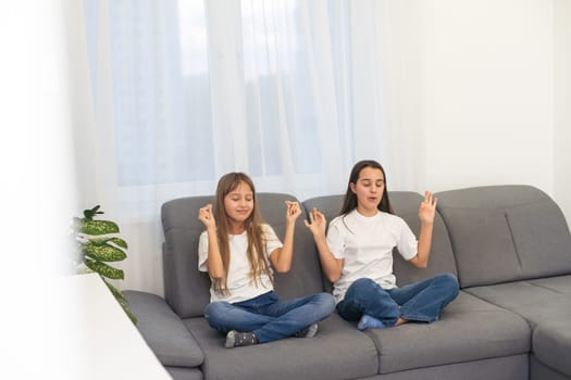 People, relationships, family, relaxation, yoga and meditation concept. girls sitting on bed, looking up, making mudra gesture, praying or meditating. High quality photo