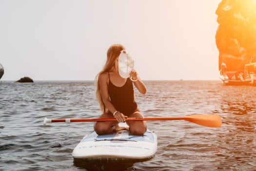 Close up shot of beautiful young caucasian woman with black hair and freckles looking at camera and smiling. Cute woman portrait in a pink bikini posing on a volcanic rock high above the sea