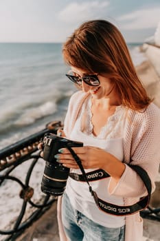 Woman travel sea. Young Happy woman in a long red dress posing on a beach near the sea on background of volcanic rocks, like in Iceland, sharing travel adventure journey