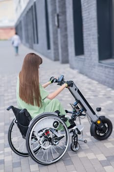 A woman in a wheelchair with an assistive device for manual control. Electric handbike