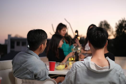 Male and female friends talking and sharing nice moments together at the rooftop party.