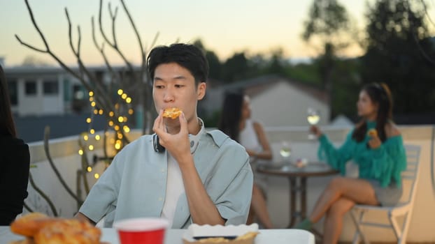 Friends gathered and celebrating together at dinner party on rooftop in the evening.