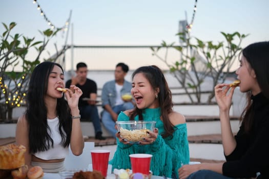 Happy young people gathered together having fun enjoy chill at outdoor rooftop party in the evening