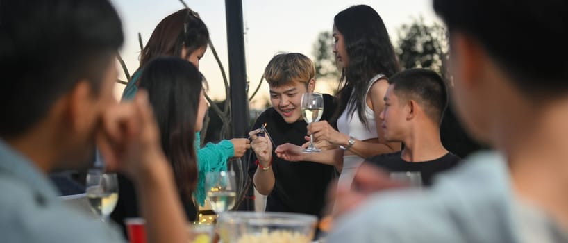 Group of happy friends lighting sparklers while celebrating at rooftop. Holiday celebration, festive and friendship concept.