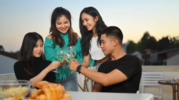 Group of cheerful people having fun while toasting with alcohol on a rooftop party.