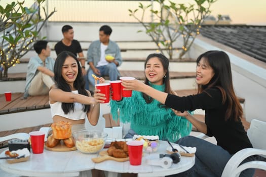 Group of friends celebrating happy hour and toasting drinks rooftop party.