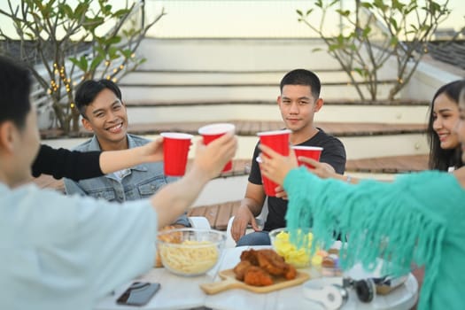 Group of friends celebrating happy hour and toasting drinks rooftop party.