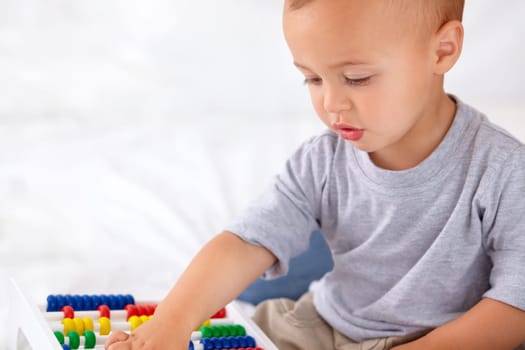 Abacus, math and boy baby learning, playing and teaching for child development on bed. Preschool, youth and closeup of kid, infant or toddler with counting for toy in bedroom or nursery at home