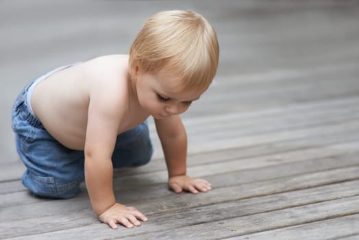 Toddler, playing on floor outdoor for development with relax, curiosity and early childhood in backyard of home. Baby, child and crawling on ground for wellness, milestone or exploring with innocence.