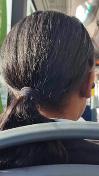 dark-haired girl sits with her back, hair tied with an elastic band. High quality photo