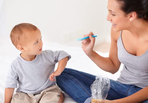 Bonding, bed and mother feeding baby porridge for health, wellness and nutrition breakfast. Child development, eating and young mom with boy kid, infant or toddler enjoying a meal in bedroom at home