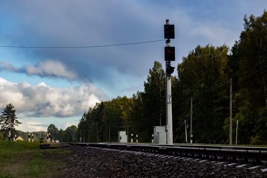 Railroad rails and traffic light with a red light bulb in forest