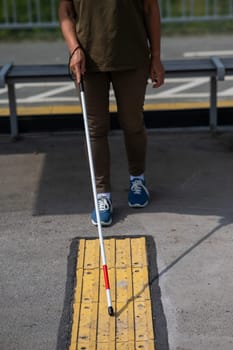 Close-up of the legs of an elderly blind woman at a bus stop