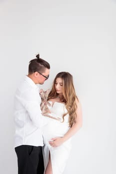 A young couple of expectant parents hold a cat in the arms