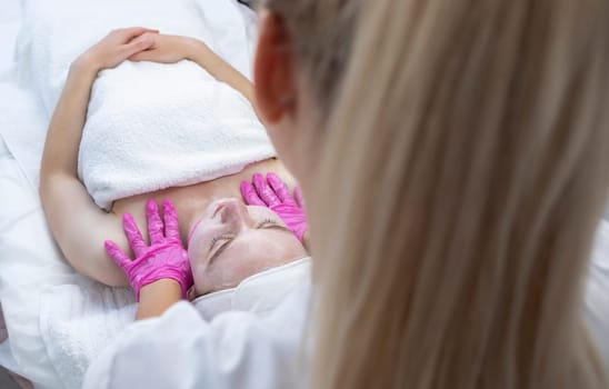 Beautician does lymphatic drainage facial massage to patient. Beautiful Caucasian Woman Gets Beauty Treatment. Relaxation, Body Care And Wellness. Horizontal Plane. High quality photo