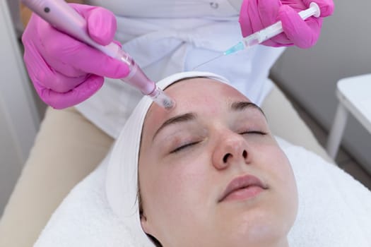Cosmetologist Applying Peeling For Mesotherapy Injection With Dermapen On Face, Forehead Area Of Young Woman For Rejuvenation In Spa Saloon. Patient Getting Needle Mesotherapy, Skincare. Horizontal