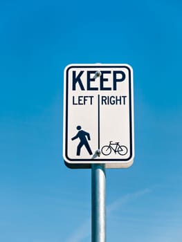 Bicycle and pedestrian shared route sign on clear sky background.