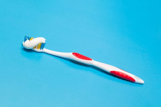 Toothbrush and toothpaste on a blue background close up