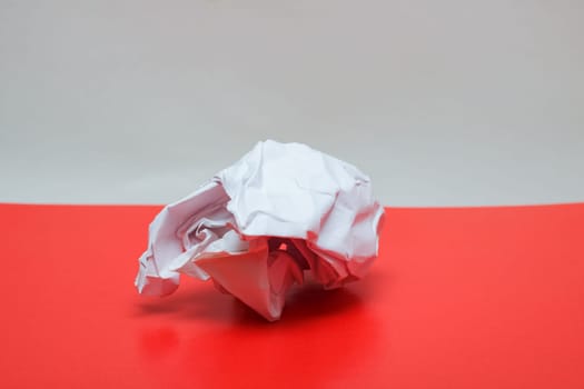 Crumpled paper close up on a red table, incomplete letter