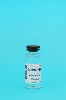 Vertical photo of an empty glass bottle from the Covid-19 vaccine on a blue background. Medical concept.