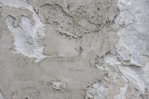 Abstract background of a gray concrete wall unevenly covered with cement.