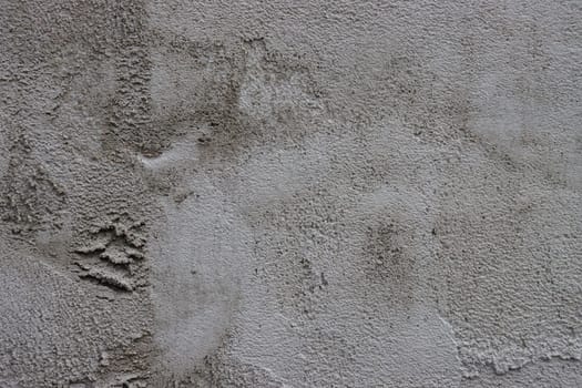 Abstract background of a gray concrete wall unevenly plastered and covered with cement.....