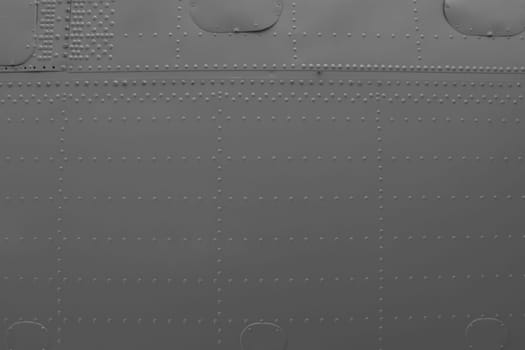 Aircraft skin close up. Rivets on gray metal. Aluminum surface of the aircraft fuselage.