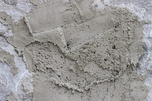 The wall is covered with rough putty. Abstract background of a gray concrete wall unevenly covered with cement.