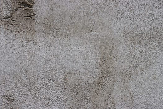 Abstract background of a gray concrete wall unevenly plastered and covered with cement.....