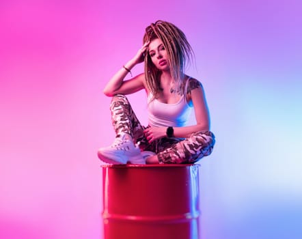 sexy girl with braided dreadlocks on her head in neon light on light background copy paste