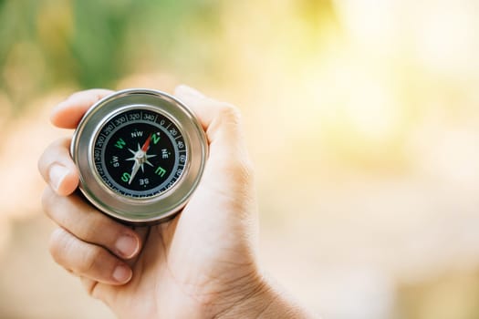 In the forest a hiker navigates confusion with a compass in hand. The compass grasped by the traveler represents topography and discovery in the midst of nature beauty.