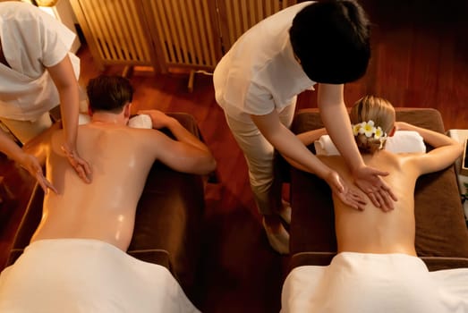 Top view couple customer enjoying relaxing anti-stress spa massage and pampering with beauty skin recreation leisure in warm candle lighting ambient salon spa at luxury resort or hotel. Quiescent