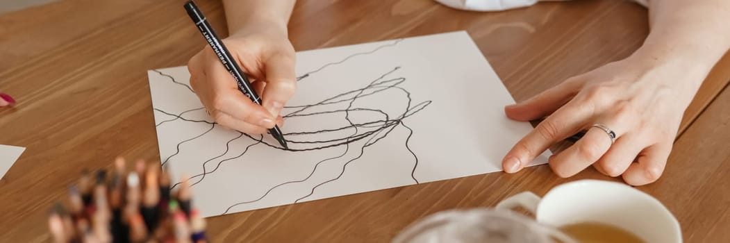 TVER, RUSSIA - FEBRUARY 25, 2023: Woman draws neurographics at table at a psychological session, neurographic pencil drawing to remove restrictions, art therapy.