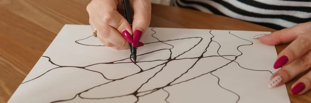 TVER, RUSSIA - FEBRUARY 25, 2023: Woman draws neurographics at table at a psychological session, neurographic pencil drawing to remove restrictions, art therapy.