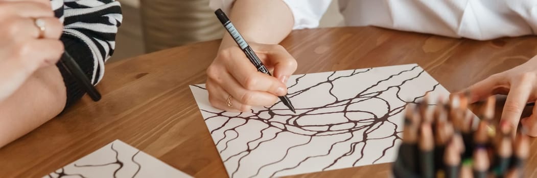 TVER, RUSSIA - FEBRUARY 25, 2023: Womans draws neurographics at table at a psychological session, neurographic pencil drawing to remove restrictions, art therapy.