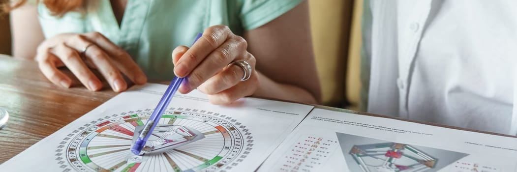 Tver, Russia - August 2, 2021. A woman in a cafe at a table is studying the design of a person. The concept of studying esoteric sciences. A bodigraph or a map of a person on an A4 sheet