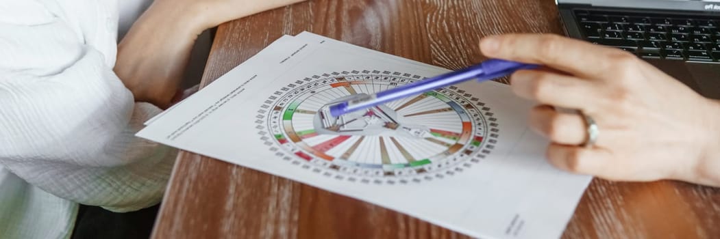 Tver, Russia - August 2, 2021. A woman in a cafe at a table is studying the design of a person. The concept of studying esoteric sciences. A bodigraph or a map of a person on an A4 sheet