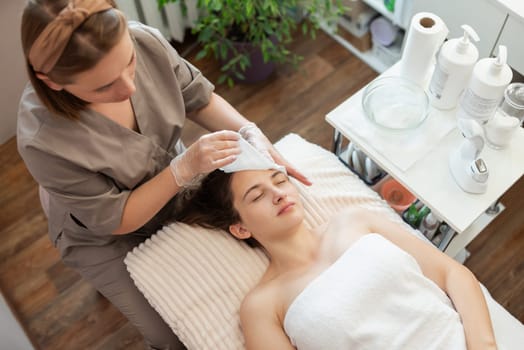 Professional cosmetologist executing cleaning of a face in modern health and beauty clinic