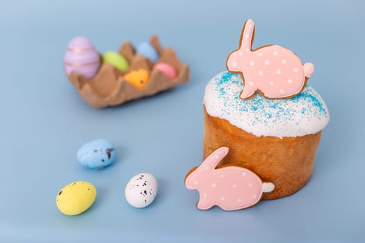 Beautiful easter still life with gingerbread in the form of a rabbit on an Easter cake, small decorative multicolored eggs lie next to it.