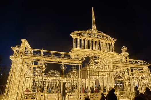 Russia, Peterhof, St.Petersburg, 07 January 2024: Magical illumination of the building of an ice rink decorated with light reliefs of the city's attractions, railway station, Christmas decorations. High quality photo