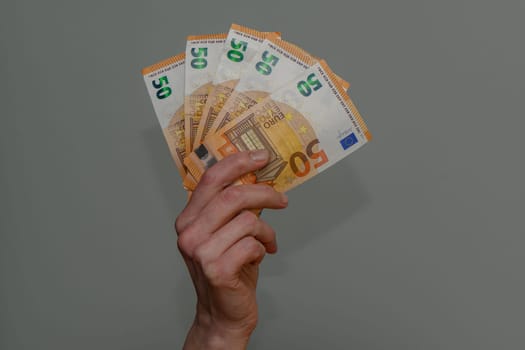 50 euro bills in hand on gray background