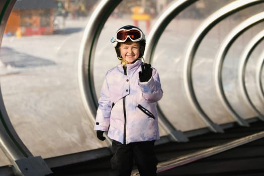 A girl on skis stands on a carpet ski lift in a tunel