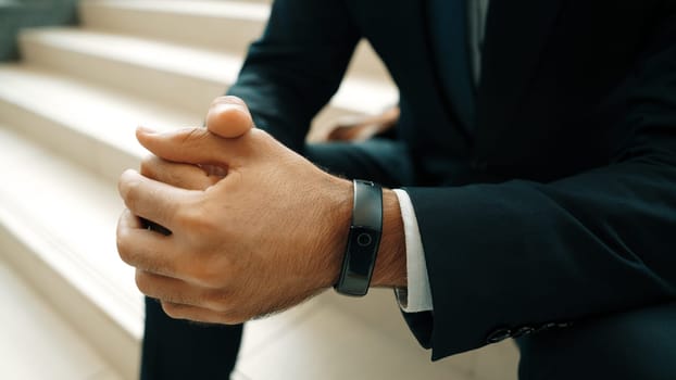 Closeup image of skilled project manager hands wear smart watch while sitting at stair. Professional business man waiting for project manager while clasping hands together. Focus on hands. Exultant.