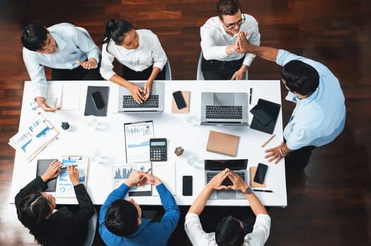 Top view diverse office employee worker high five after making agreement on strategic business marketing planning. Teamwork and positive attitude create productive and supportive workplace. Prudent